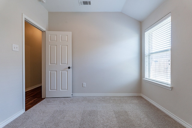 carpeted empty room with plenty of natural light and lofted ceiling