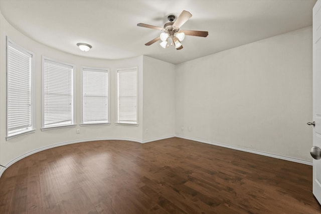 unfurnished room featuring ceiling fan, baseboards, and dark wood finished floors