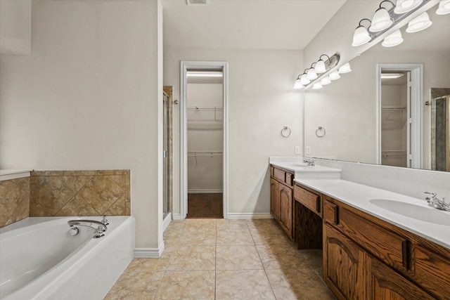 bathroom featuring a bath, a shower stall, a walk in closet, and a sink