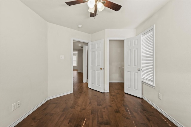 unfurnished bedroom with ceiling fan, baseboards, and dark wood-style flooring