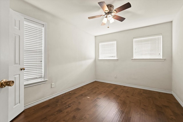 unfurnished room with dark wood finished floors, a ceiling fan, and baseboards