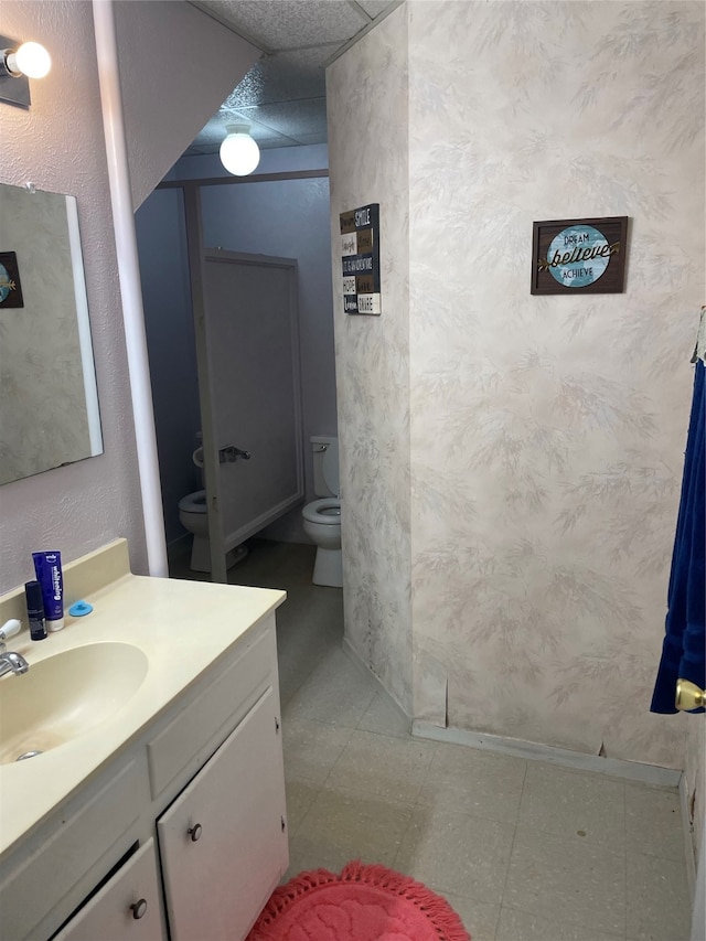 bathroom with tile patterned floors, a paneled ceiling, toilet, and vanity