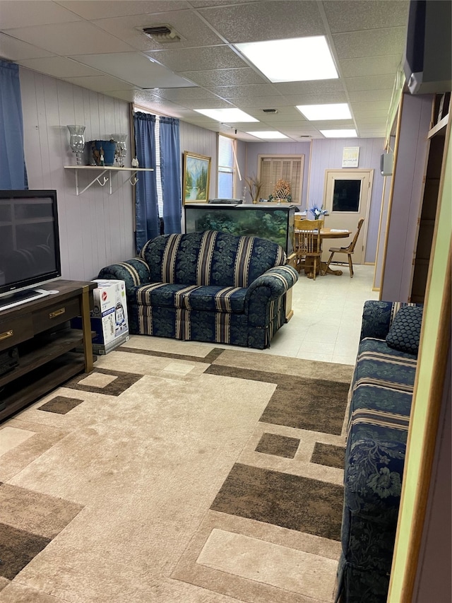 carpeted living room featuring a paneled ceiling and wooden walls