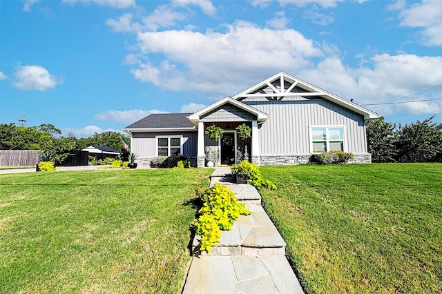 view of front of property featuring stone siding, a front lawn, and board and batten siding