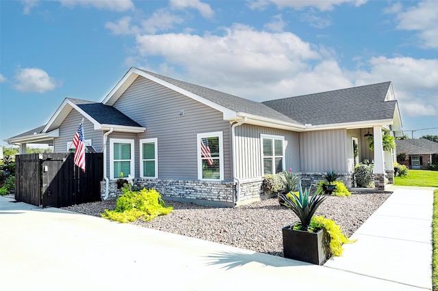 view of front facade featuring stone siding, a shingled roof, and board and batten siding