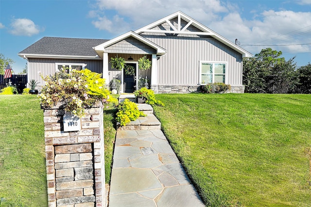 view of front of property with board and batten siding, a front yard, and roof with shingles