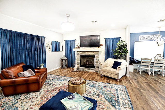 living area featuring a fireplace, wood finished floors, visible vents, and baseboards