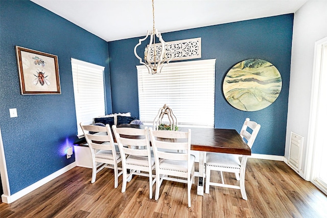 dining room with a notable chandelier, baseboards, and wood finished floors