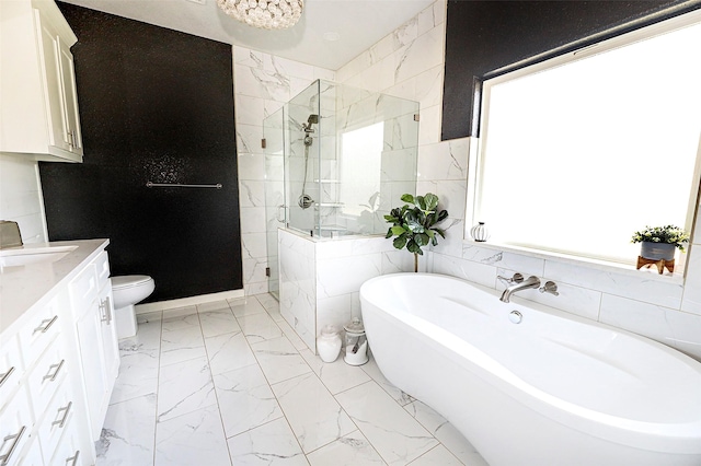 bathroom featuring a freestanding tub, vanity, tile walls, marble finish floor, and a shower stall