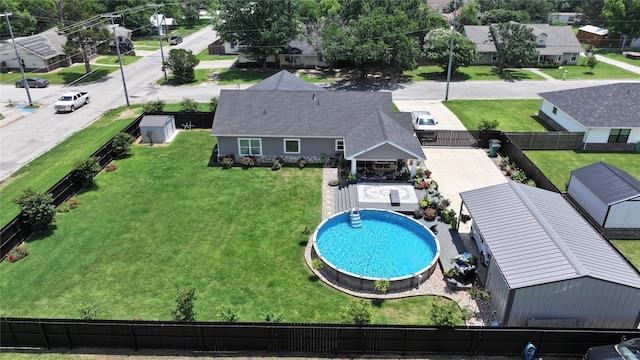 view of pool featuring a storage shed, fence, an outdoor structure, and a lawn