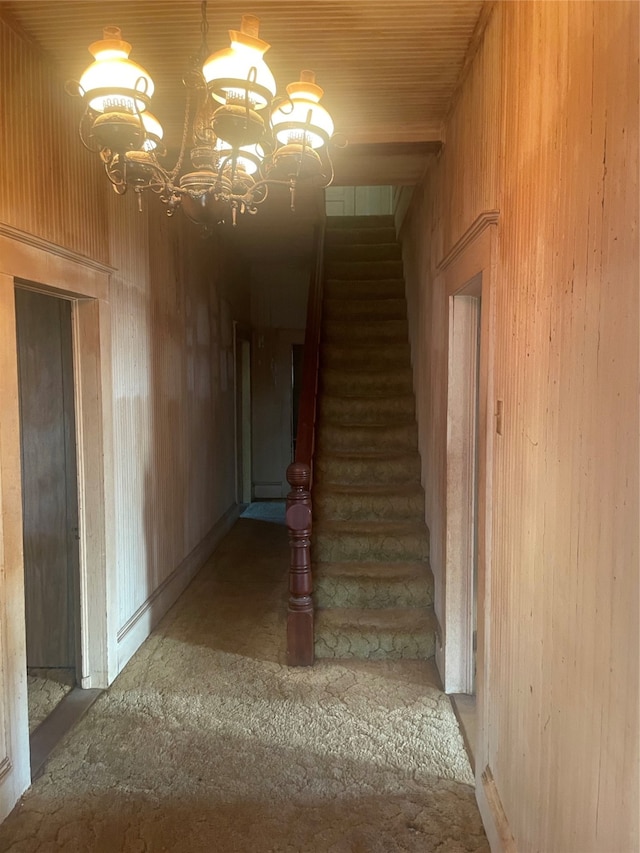 hall featuring wooden walls and an inviting chandelier