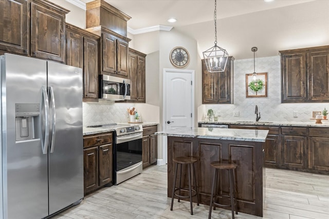 kitchen with sink, tasteful backsplash, a center island, hanging light fixtures, and appliances with stainless steel finishes