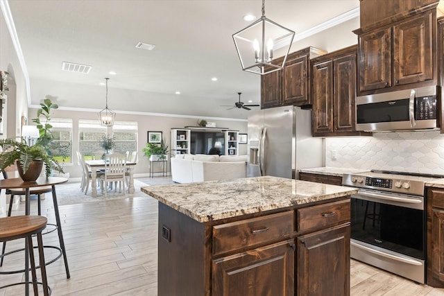 kitchen with visible vents, backsplash, a center island, crown molding, and appliances with stainless steel finishes