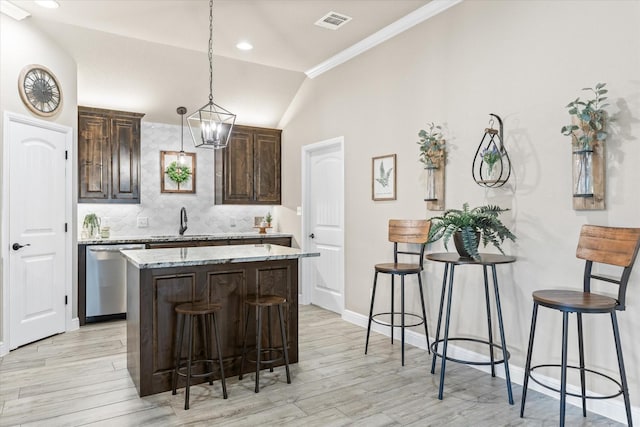 kitchen featuring visible vents, stainless steel dishwasher, a center island, dark brown cabinetry, and lofted ceiling