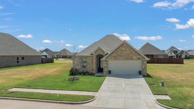 french country home featuring fence, a front yard, a garage, stone siding, and driveway