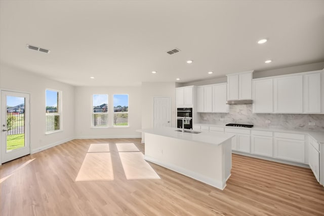 kitchen featuring white cabinets, backsplash, light wood-type flooring, and black appliances