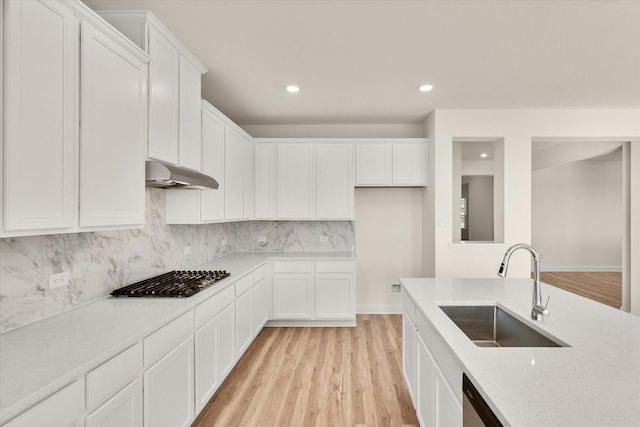 kitchen with decorative backsplash, white cabinetry, sink, and light hardwood / wood-style flooring