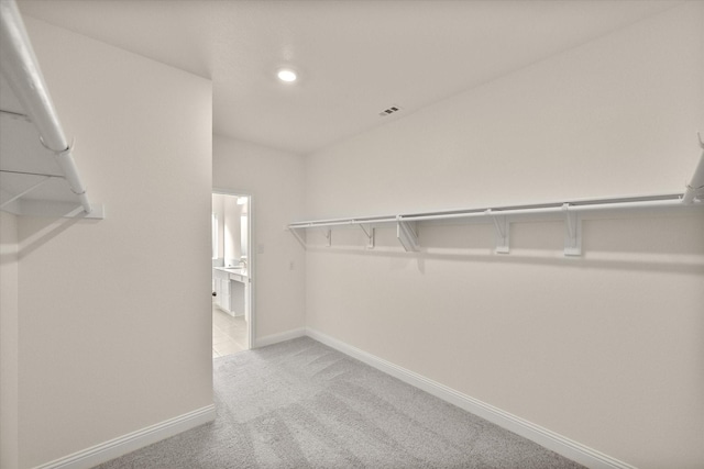 walk in closet with light carpet