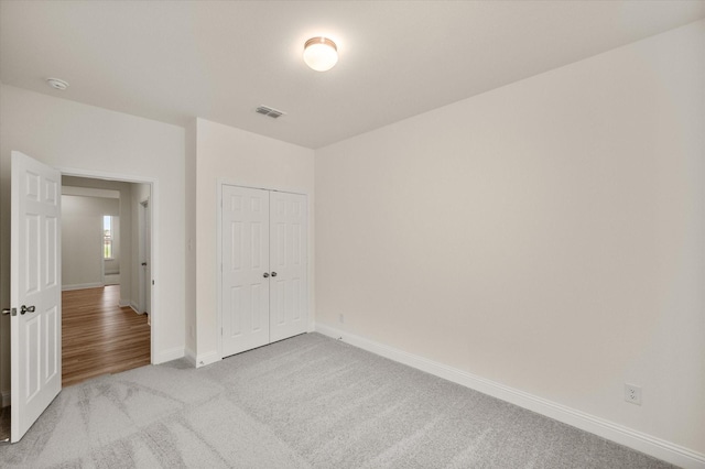 unfurnished bedroom with light colored carpet and a closet