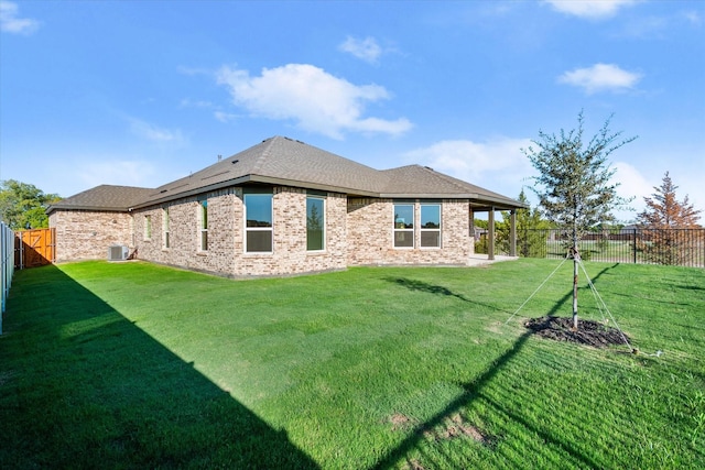 rear view of property with central AC unit and a yard