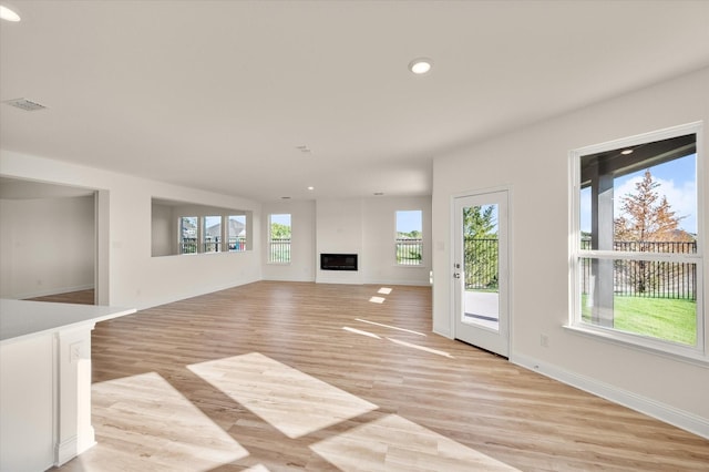 unfurnished living room featuring a healthy amount of sunlight and light hardwood / wood-style floors