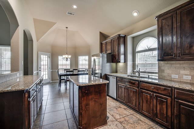 kitchen featuring decorative backsplash, appliances with stainless steel finishes, light stone counters, and a kitchen island