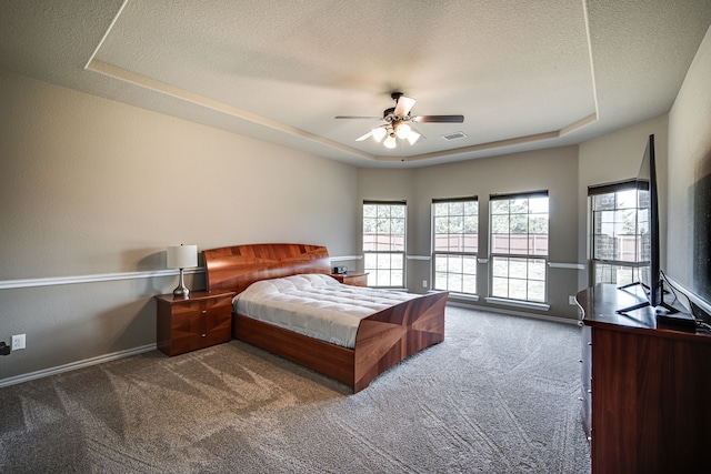 carpeted bedroom with ceiling fan, a raised ceiling, and a textured ceiling