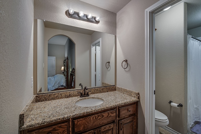 bathroom featuring a textured ceiling, vanity, and toilet