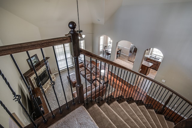 stairs with ceiling fan, high vaulted ceiling, and carpet floors