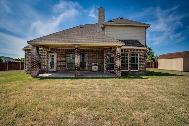 back of property featuring a storage unit, a yard, and a patio