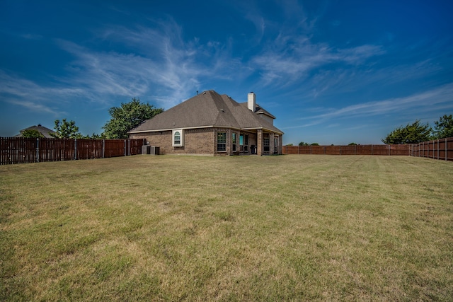 rear view of property with central AC unit and a lawn