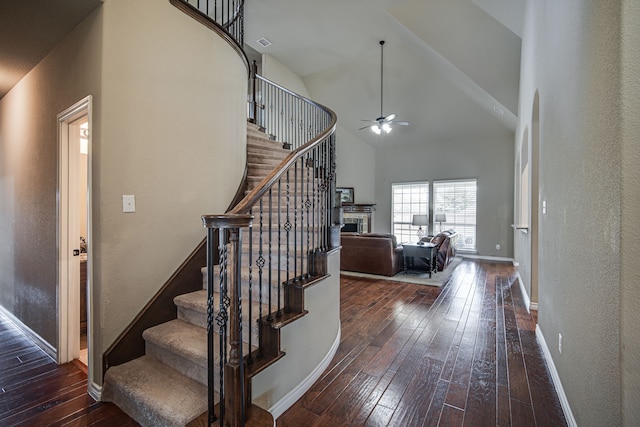 stairs with ceiling fan, high vaulted ceiling, and wood-type flooring