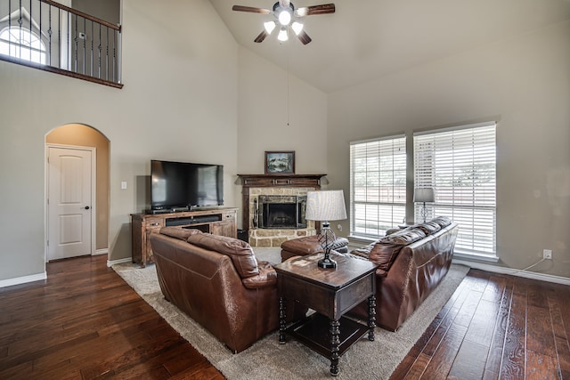 living room featuring ceiling fan, high vaulted ceiling, a stone fireplace, and wood-type flooring