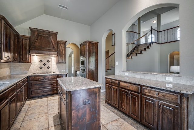 kitchen featuring backsplash, custom range hood, a center island, light tile patterned flooring, and stainless steel appliances