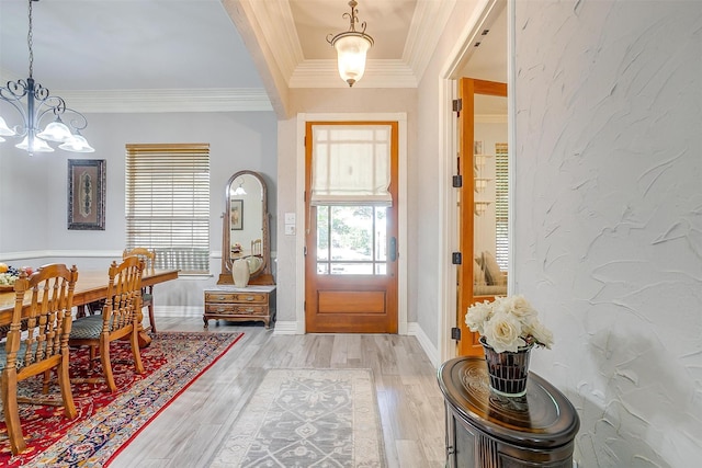 foyer with hardwood / wood-style flooring, ornamental molding, and an inviting chandelier