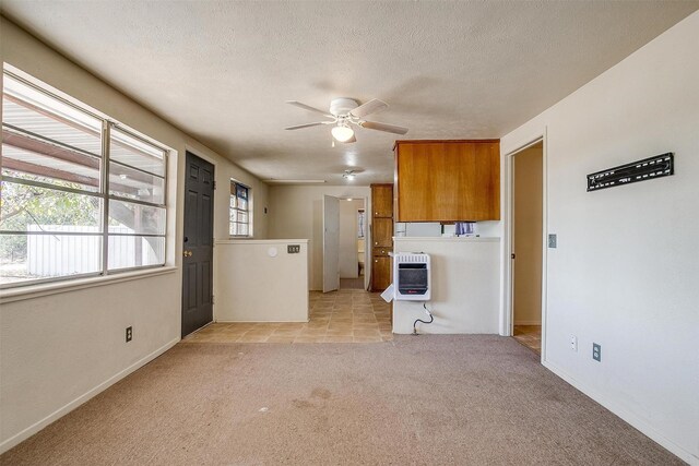 spare room with plenty of natural light, light colored carpet, a textured ceiling, and heating unit