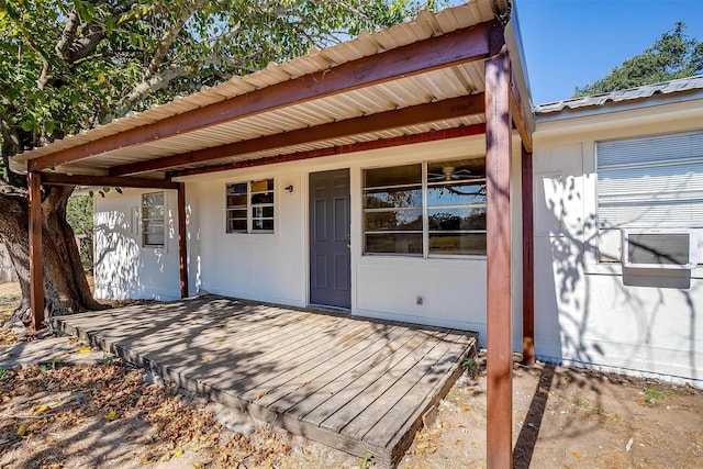 entrance to property with metal roof, cooling unit, and a wooden deck