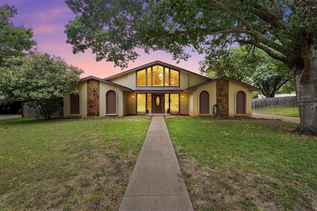 mid-century home with brick siding, fence, and a lawn