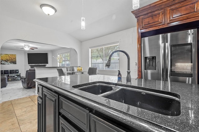 kitchen with a ceiling fan, stainless steel refrigerator with ice dispenser, a sink, arched walkways, and lofted ceiling
