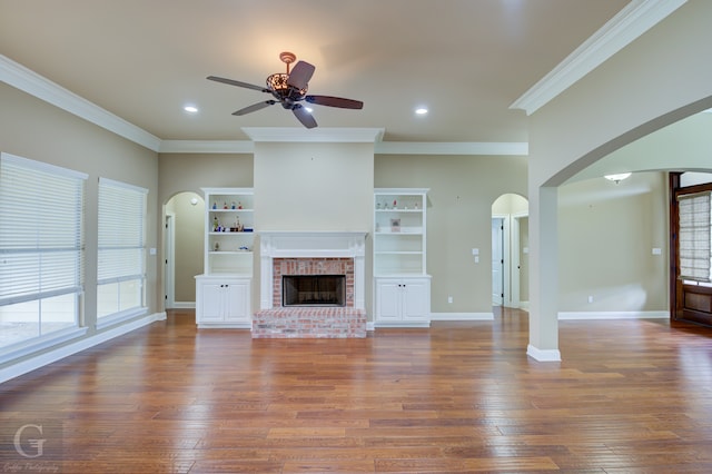 unfurnished living room with ceiling fan, hardwood / wood-style flooring, a fireplace, and crown molding