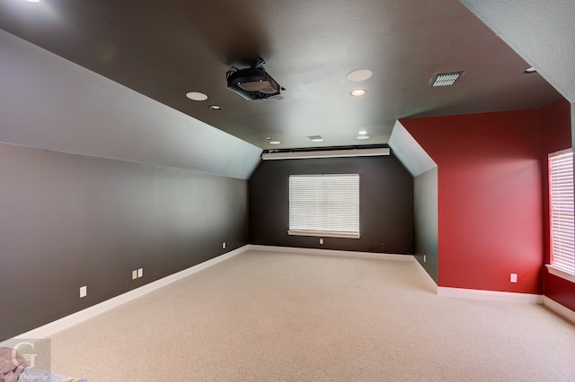 additional living space with carpet floors and vaulted ceiling