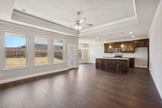 unfurnished living room featuring dark wood-type flooring, ceiling fan with notable chandelier, ornamental molding, and a tray ceiling