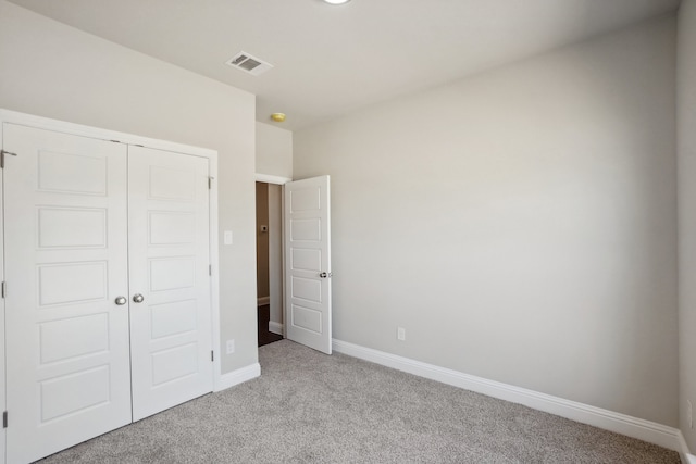 unfurnished bedroom with light colored carpet and a closet