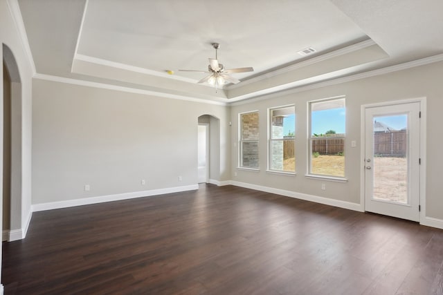 spare room with ornamental molding, ceiling fan, a tray ceiling, and dark wood-type flooring