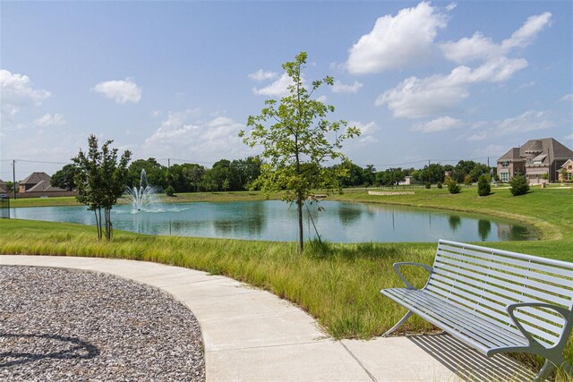 view of property's community featuring a lawn and a water view