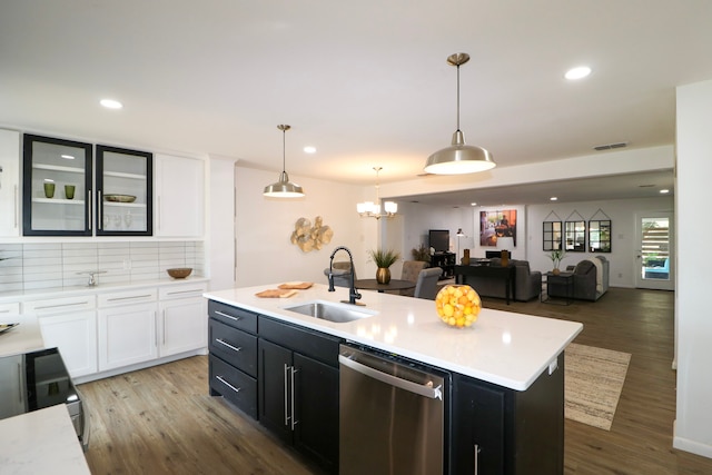 kitchen with sink, stainless steel dishwasher, an island with sink, pendant lighting, and wood-type flooring