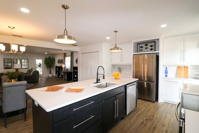 kitchen featuring sink, hardwood / wood-style floors, decorative light fixtures, a kitchen island with sink, and appliances with stainless steel finishes