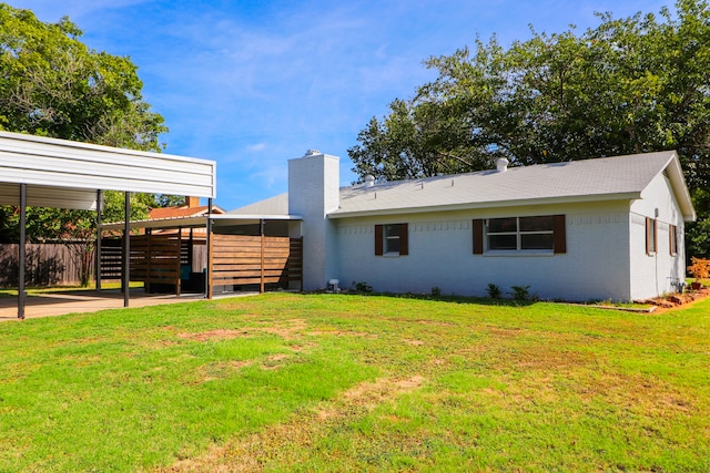 rear view of property with a carport and a lawn