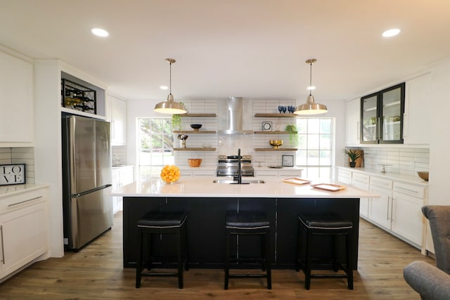 kitchen featuring appliances with stainless steel finishes, tasteful backsplash, a wealth of natural light, and wall chimney range hood