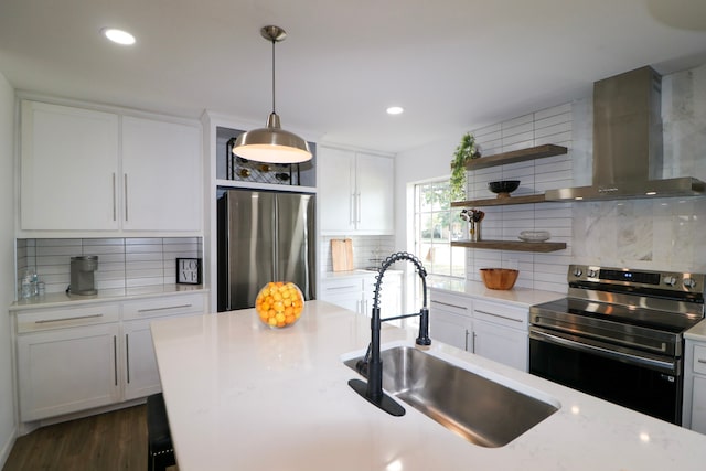 kitchen with tasteful backsplash, white cabinetry, wall chimney exhaust hood, and appliances with stainless steel finishes